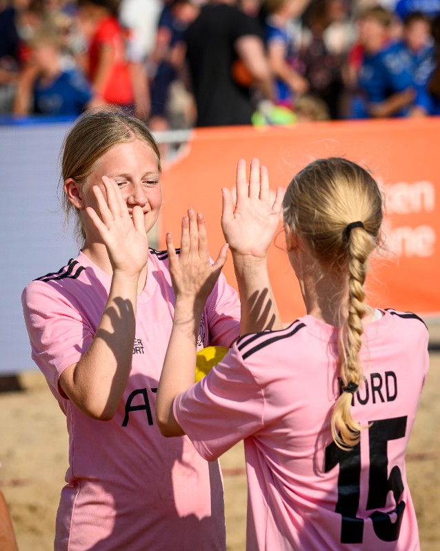Två flickor gör high-five på planen